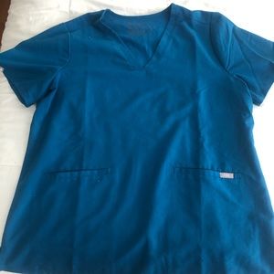 FIGS Women’s 3-Pocket scrub top in Alps Blue.